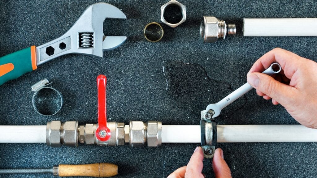 Plumber repairing a pipe valve with an adjustable wrench in Aurora