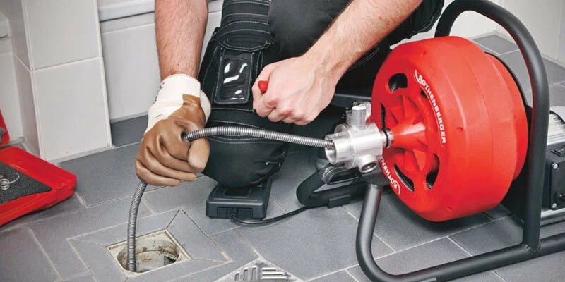 Plumber using a drain-cleaning machine in Aurora