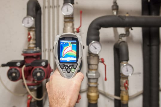 Plumber using a thermal imaging camera to inspect pipes in Aurora